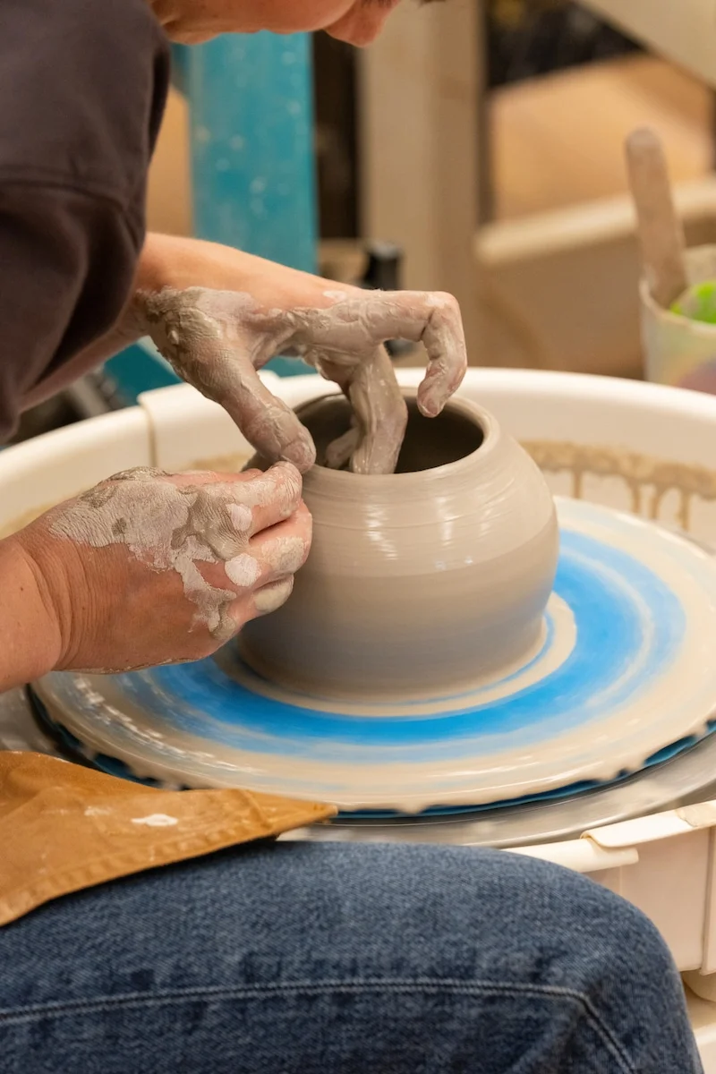 Hands shaping clay on a spinning potter's wheel