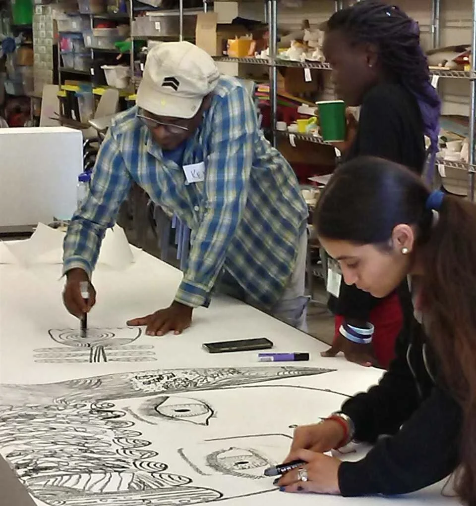 People collaborating on a large drawing on paper in an art workshop.