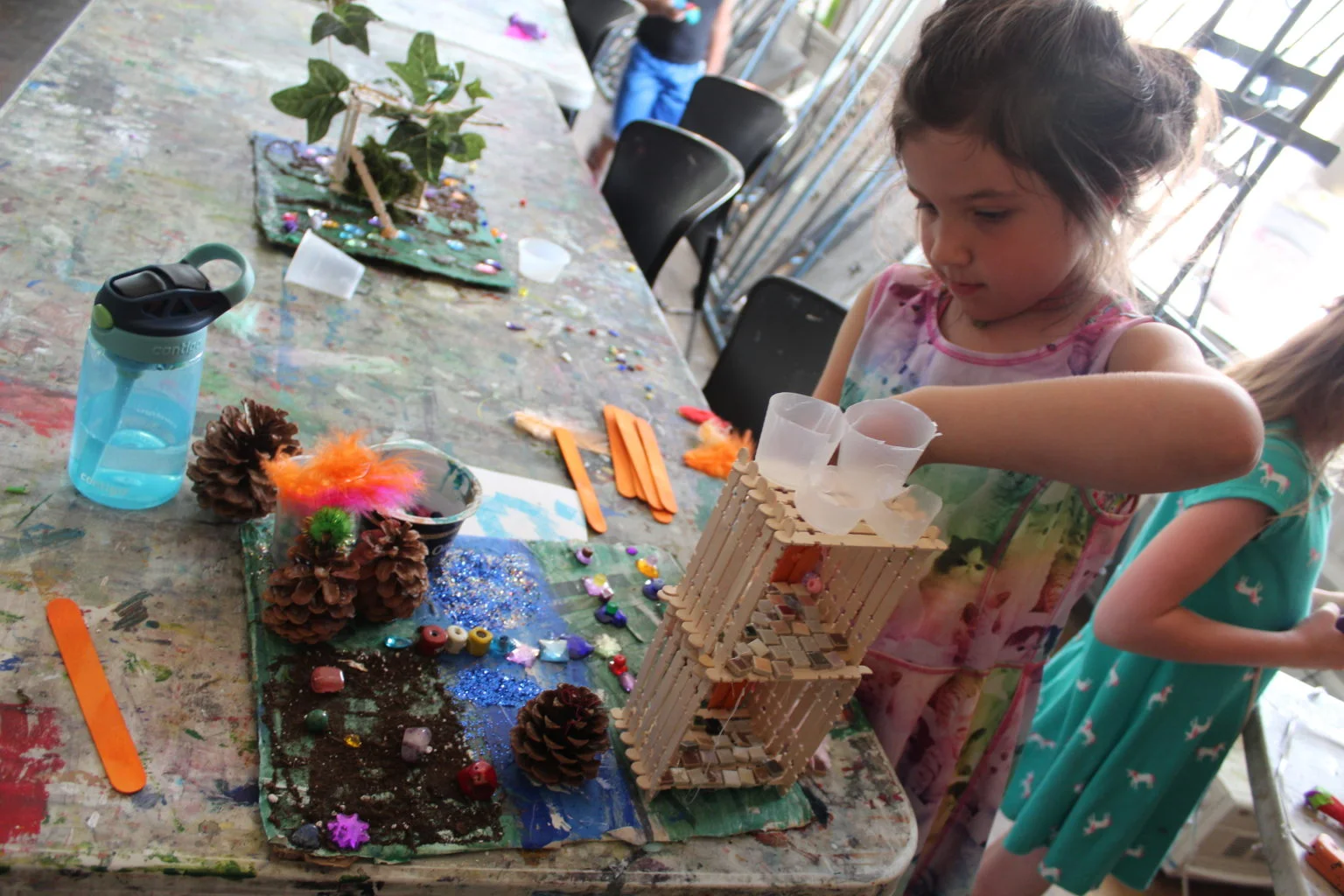 Children engaged in arts and crafts with colorful materials on a messy table.